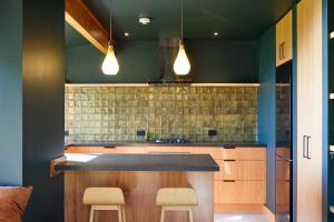 a kitchen with green walls and a counter with stools at The Whole Front House in Hapuku +139 photos