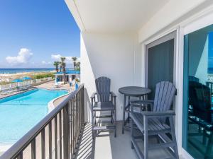 balcón con sillas, mesa y piscina en Sea Oats #201, en Fort Walton Beach