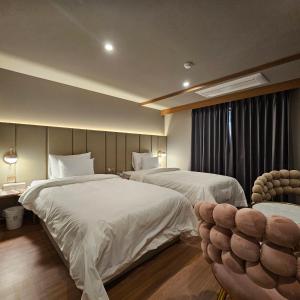 a hotel room with two beds and a chair at Denbasta Hotel Choeup in Busan