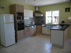 a kitchen with wooden cabinets and a white refrigerator at Maison à Salignac-Eyvigues avec terrasse, Wifi et parking - FR-1-616-116 in Salignac Eyvigues