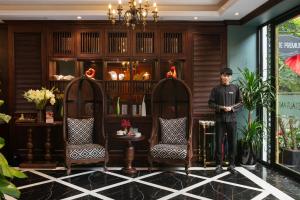 a man standing in a room with two chairs at Salute Premium Hotel & Spa in Hanoi