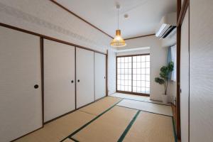 神户LN07 三宮中心14名まで宿泊可能! 交通至便! Sannomiya Base 2的空的走廊,有白色的门和盆栽