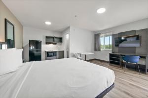 a large white bedroom with a large bed and a desk at Southern Suites Columbus in Columbus