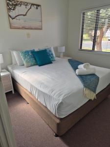 a bed with blue and white pillows and a window at Serenity Diamond Beach in Diamond Beach +40 photos