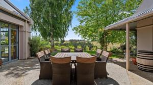 a patio with a table and chairs in a yard at Hawkdun Rise Vineyard & Accommodation in Alexandra
