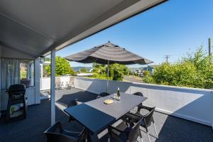 a patio with a table and an umbrella at Close to the Lake in Taupo