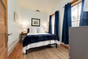 a bedroom with a bed and two windows with blue curtains at Be A Nomad - Combined Pool Home 1 blck to Beach in Jacksonville Beach