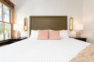 a bedroom with a large white bed with pink pillows at Be A Nomad - Combined Pool Home 1 blck to Beach in Jacksonville Beach