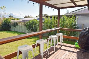 a deck with three stools and a pergola at Sea Salt Cottage - Bring your own linen. in South West Rocks