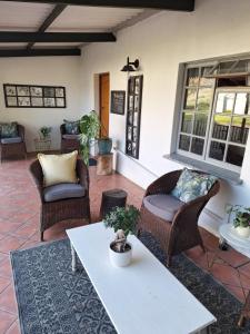 a patio with wicker chairs and a white table at Rooiheuwel Cottage in Wellington