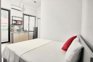 a white bedroom with a red pillow on a bed at Eco Nest Hotel & Apartment in Hanoi