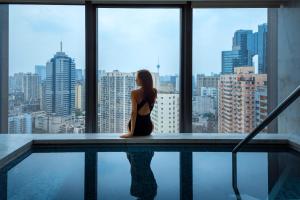 a woman sitting next to a swimming pool in a building at The Ritz-Carlton, Chengdu in Chengdu