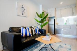a black leather couch in a living room with a table at 2-Bs Suite Adjacent to Sky Tower in Auckland