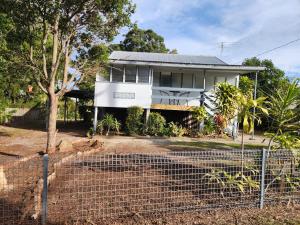 una casa blanca con una valla delante en Sandown Beachside Cottage, en Bongaree
