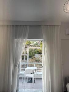 a room with white curtains and a patio with a table and chairs at Nōya Suites SR in Sarandë