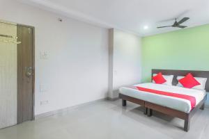 a bedroom with a bed with red pillows on it at Hotel O Gokul Residency in Kharadi