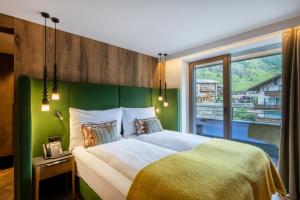 a bedroom with a large bed with a green headboard at Hotel ZERMAMA Zermatt in Zermatt