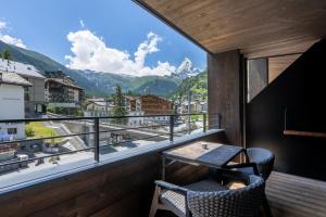 a balcony with a table and chairs and a view of mountains at Hotel ZERMAMA Zermatt in Zermatt