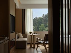 a room with a table and a chair and a window at Yanyu Yunxi Resort Hotel 烟雨云兮酒店 in Fenghuang County