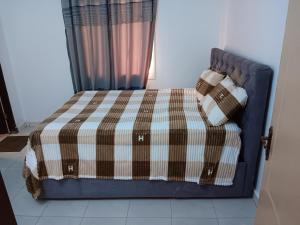 a bed with a plaid blanket and pillows on it at 3 bedroom, free Wi-fi, Aircon & Hot water in Tujering