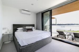 a bedroom with a large bed and a balcony at Bayfront Holiday Retreat with Parking in Batemans Bay +11 photos