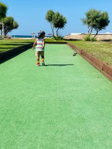 a young child walking on a field of green grass at Thalassa Beach Resort in Vokolidha