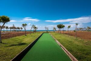 a green walkway with palm trees on the beach at Thalassa Beach Resort in Vokolidha