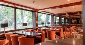 a restaurant with orange chairs and tables and windows at PLAZA Hotel Gelsenkirchen in Gelsenkirchen