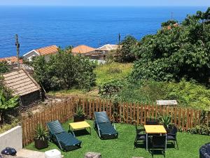 a patio with chairs and tables and the ocean at Lombada Villa Comfort in Ponta Delgada