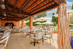 an outdoor patio with tables and chairs and umbrellas at Golf Hôtel de Valescure & Spa NUXE in Saint-Raphaël