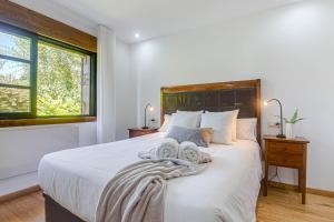 a bedroom with a white bed with a wooden headboard at Elysian Villa in Miño +25 photos