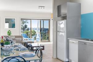 a kitchen and a living room with a table and a couch at Spyglass Mollymook in Mollymook