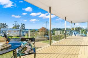 a large deck with a table and chairs on it at Spyglass Mollymook in Mollymook