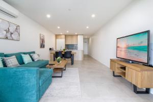 a living room with a blue couch and a flat screen tv at Stunning 1-Bed Bayside Apartment with Superb Views in Batemans Bay