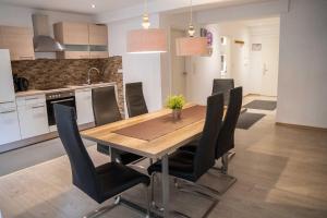 Una cocina y un comedor con mesa y sillas de madera. en Villa Nordhang - Apartment 4, en Winterberg