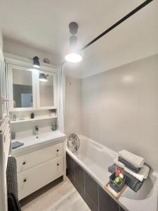 a white bathroom with a tub and a sink at La PASSERELLE in Toulouse