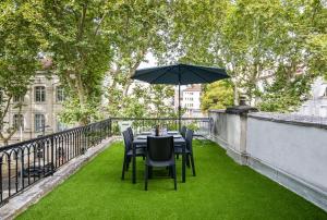 una mesa y sillas en un balcón con sombrilla en Gambetta201CahorsCityStay, en Cahors