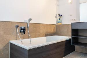 a bath tub with a shower in a bathroom at Architektenhaus c1 mit Seesicht in Öhningen +22 photos