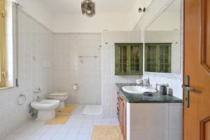 a white bathroom with a toilet and a sink at Appartamento Orto degli Ulivi in Lotzorai