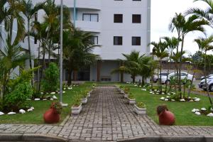 un camino de ladrillo frente a un edificio con palmeras en Apartamento Satel Praia, en Itanhaém