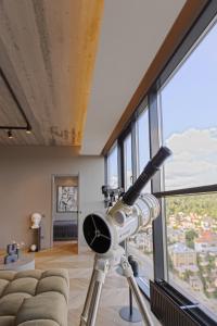 a telescope in front of a room with a couch at HOUSE38 Panoramic View Apartments SELF CHECK-IN in Kaunas