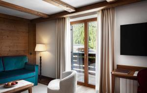 a living room with a blue couch and a window at Hotel Tyrol in Selva di Val Gardena