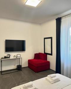 a room with a red chair and a flat screen tv at Inn Urbe Colosseo in Rome