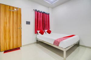 a bedroom with a bed with red curtains and a door at Hotel O Roman Inn in Nagpur
