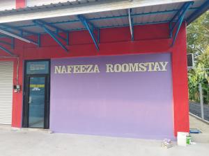 a sign on the side of a building with a door at Nafeeza Roomstay in Jertih