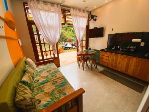 a living room with a bed and a kitchen with a table at Flats Theo Peleteiro Praia da concha Flatitacareconcha in Itacaré