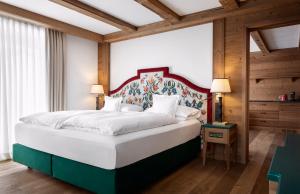 a bedroom with a large white bed with a colorful headboard at Hotel Tyrol in Selva di Val Gardena