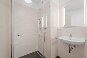 ein weißes Badezimmer mit Waschbecken und Dusche in der Unterkunft Heimathafen mit See- & Bergsicht in Friedrichshafen