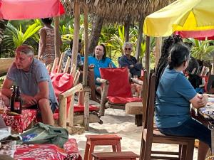 a group of people sitting in chairs under umbrellas at Les Lodges de La Buvette ÉCO LODGE RESTAURANT in Ile aux Nattes