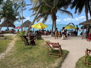 a group of people sitting at tables on the beach at Les Lodges de La Buvette ÉCO LODGE RESTAURANT in Ile aux Nattes